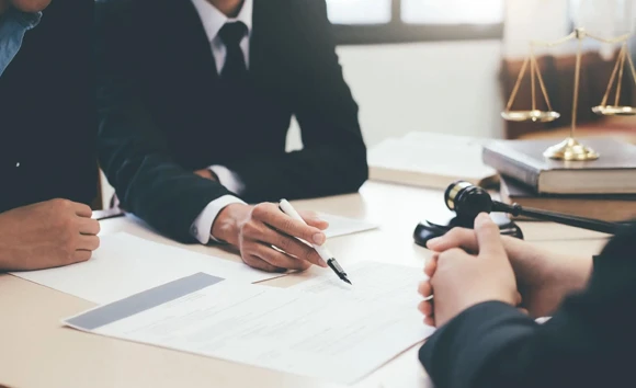 Close-up of hands interacting over legal paperwork, representing personal and professional commitment in the bail bond process and providing support to clients.
