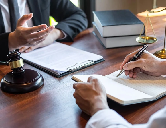 Two individuals engaged in a discussion over legal paperwork at a desk, with a gavel visible, representing collaboration in felony bail bond services.
