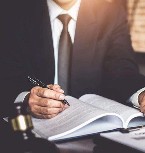 Individual making notes while reviewing legal documents, illustrating attention to detail and thoroughness in providing bail bond services.