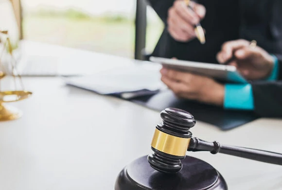 Individual sitting at a desk, writing notes and reviewing documents, representing the detailed process of securing bail bonds and providing legal support.